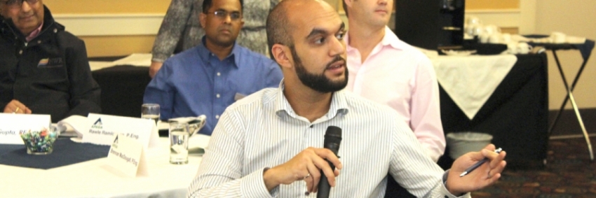 A man holding a microphone and speaking while gesturing