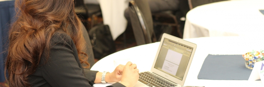 A woman sitting at a table with a laptop open, editing a document